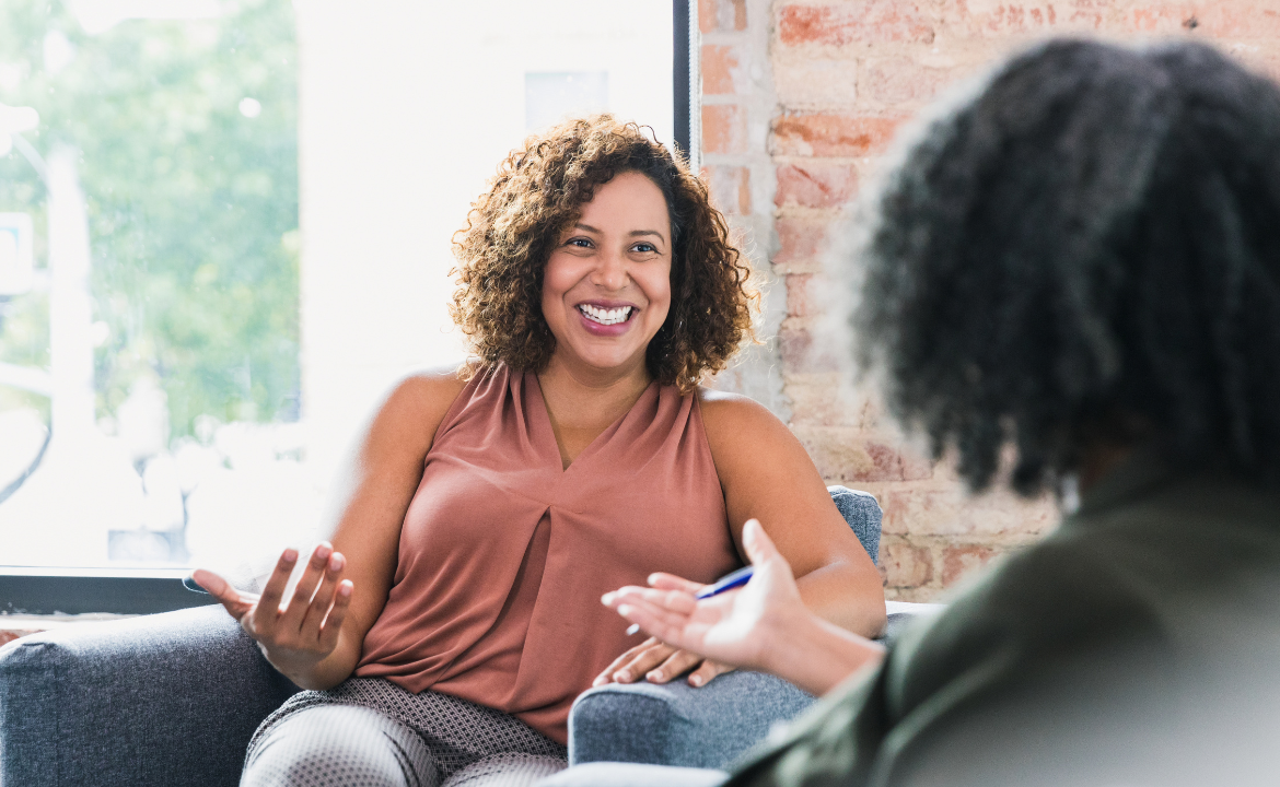 a picture of a woman smiling at a therapist who is facing away from the camera, toward the client.