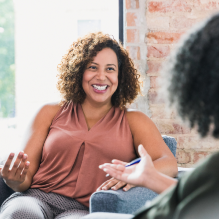 a picture of a woman smiling at a therapist who is facing away from the camera, toward the client.